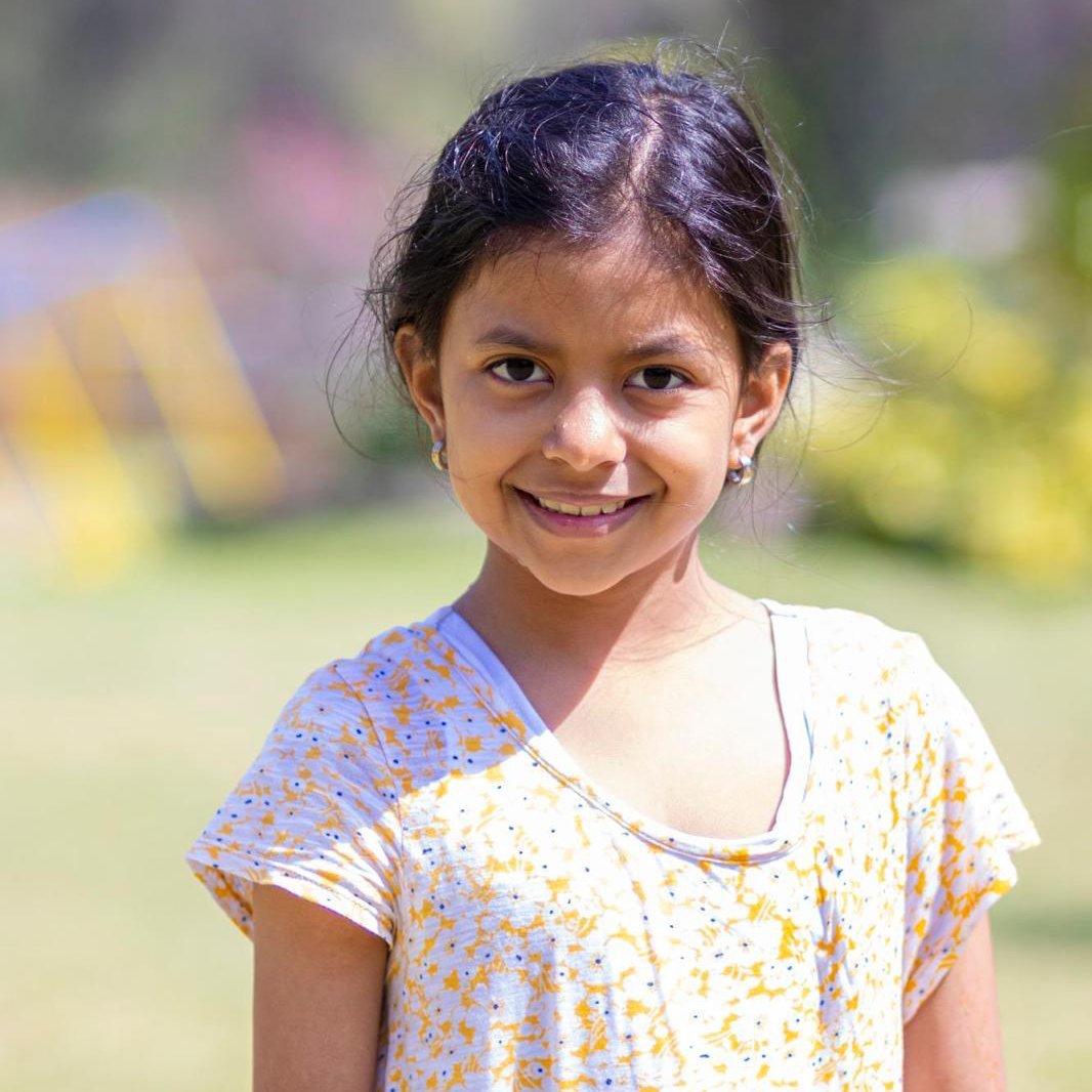 Smiling girl aged 9 with dark hair and gold earrings