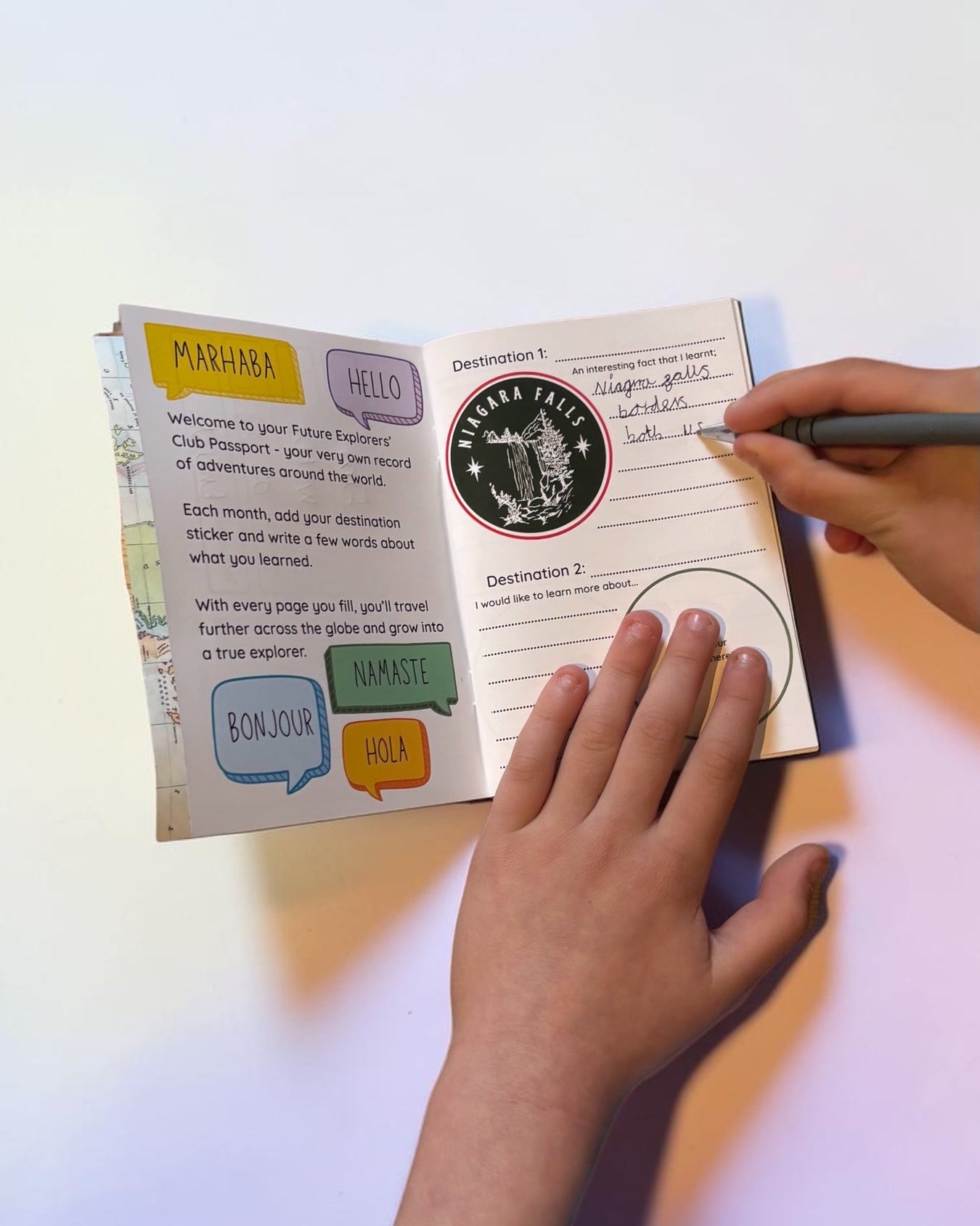 Person holding a notebook with a pen on a white surface