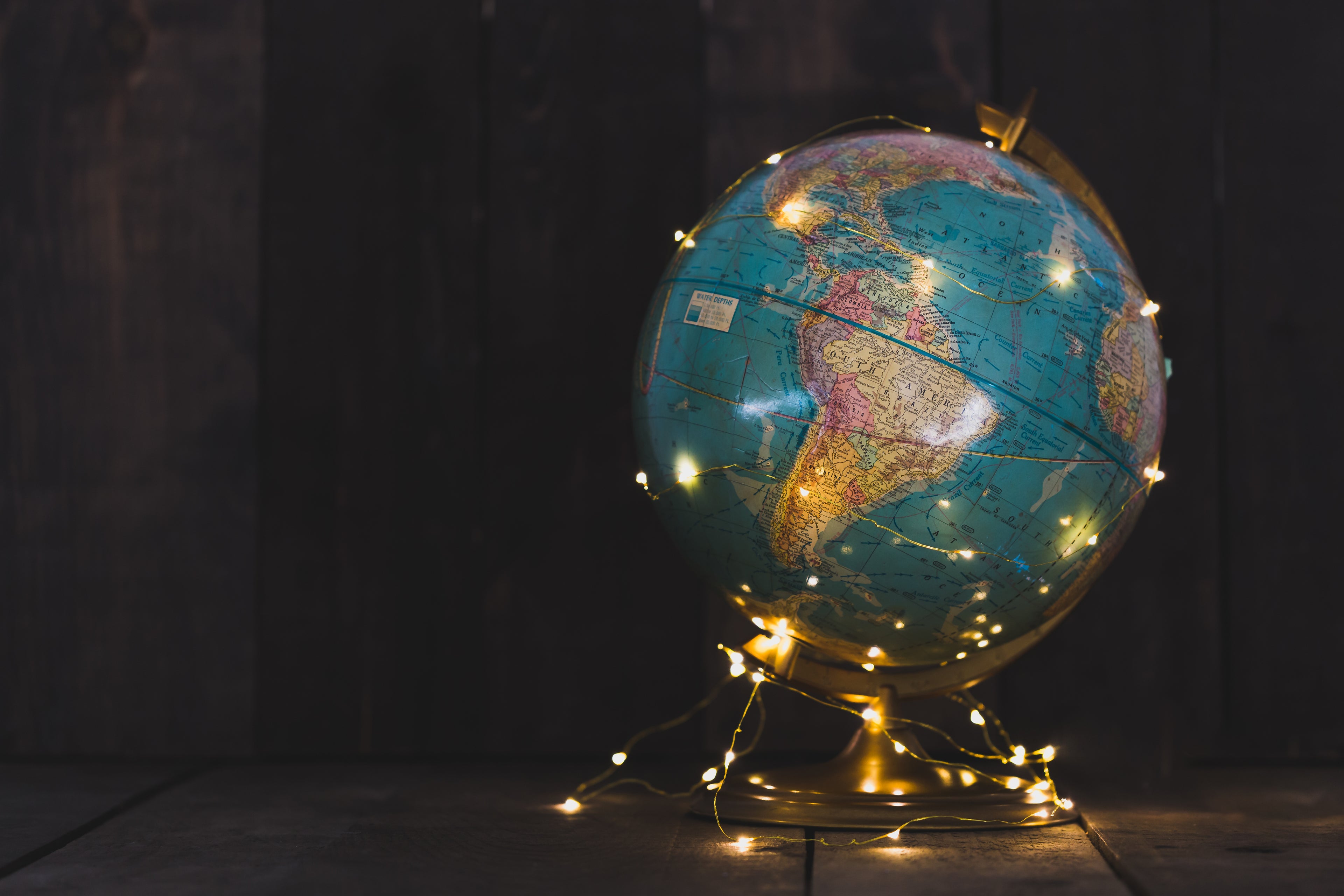 World globe lit by fairy lights against black background